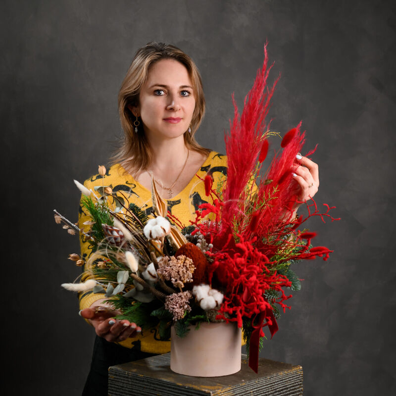 Florist holding a box arrangement with dramatic red dried botanicals