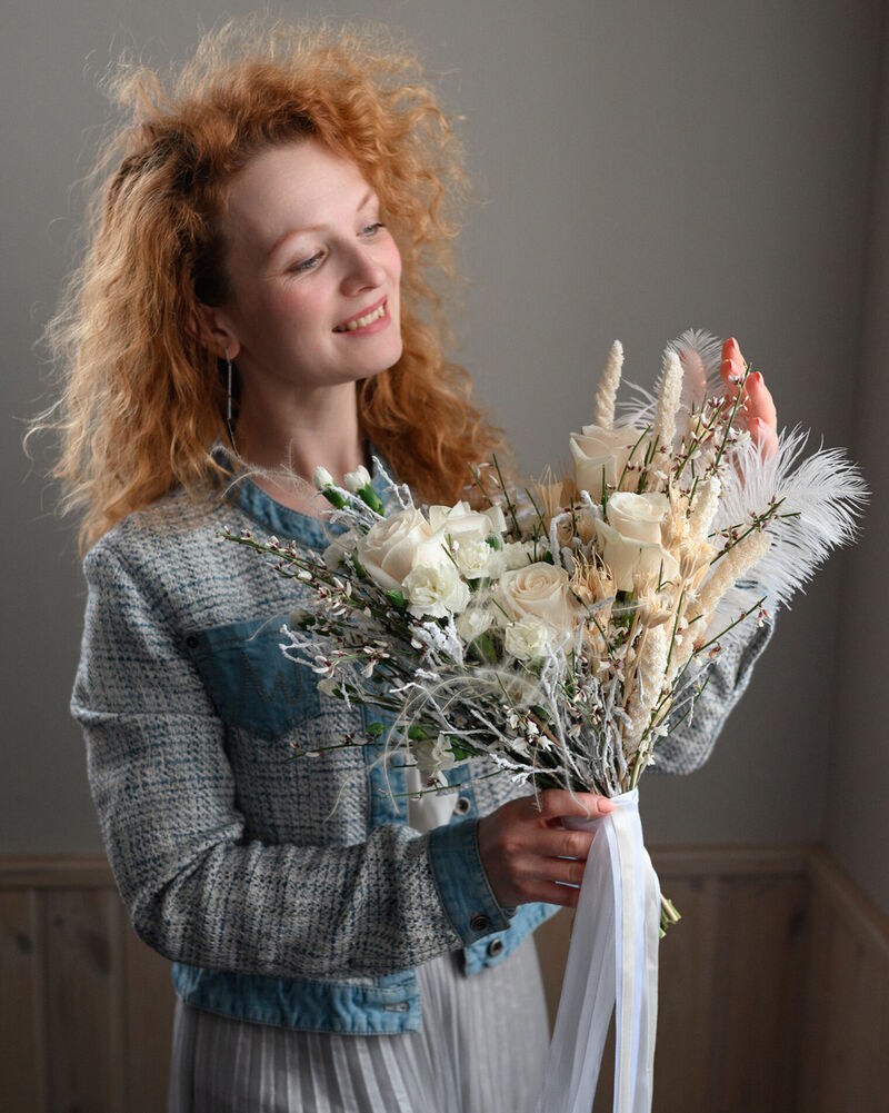 Student holding an elegant white and blush dried flower bouquet